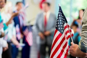 an immigrant holding a US flag in front of the crowd